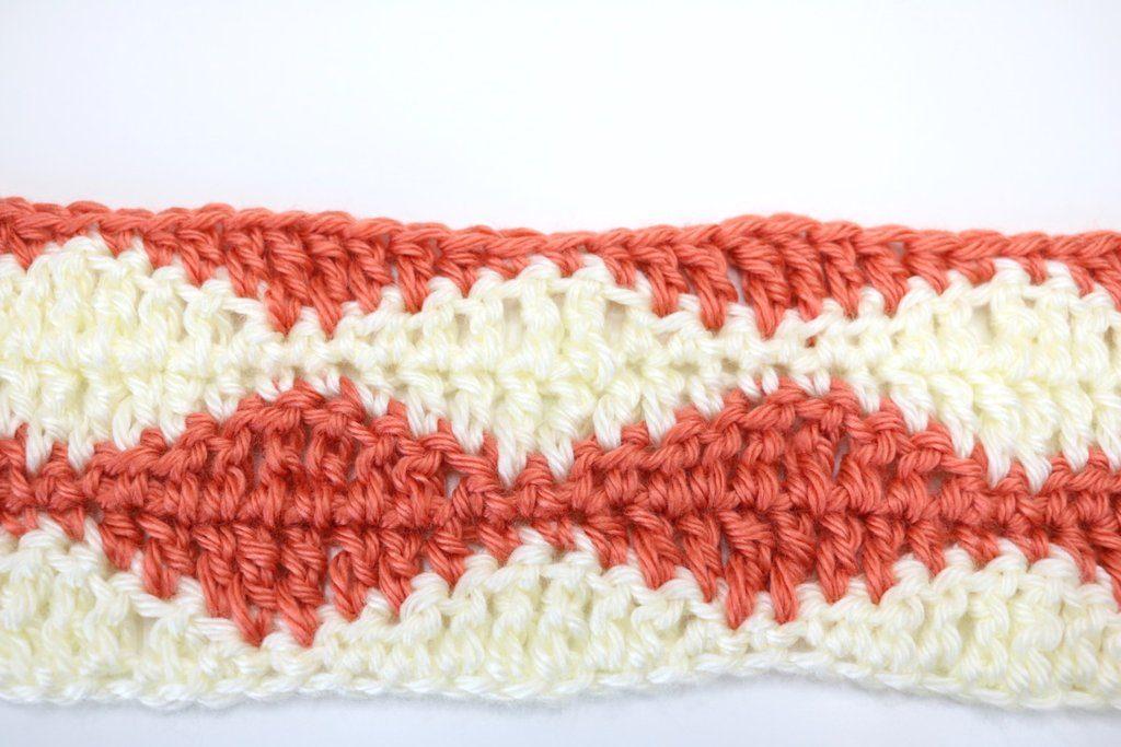 The rolling waves crochet stitch as a swatch in cream and burnt orange yarn. The swatch lays on a white background.