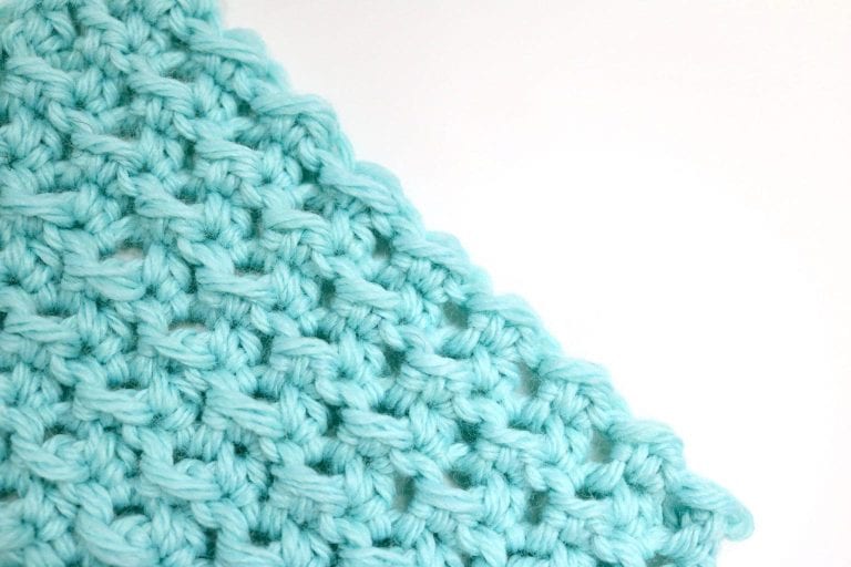 Close-up of a light blue crochet swatch using the crunch stitch pattern, showing textured ridges and soft yarn detail.