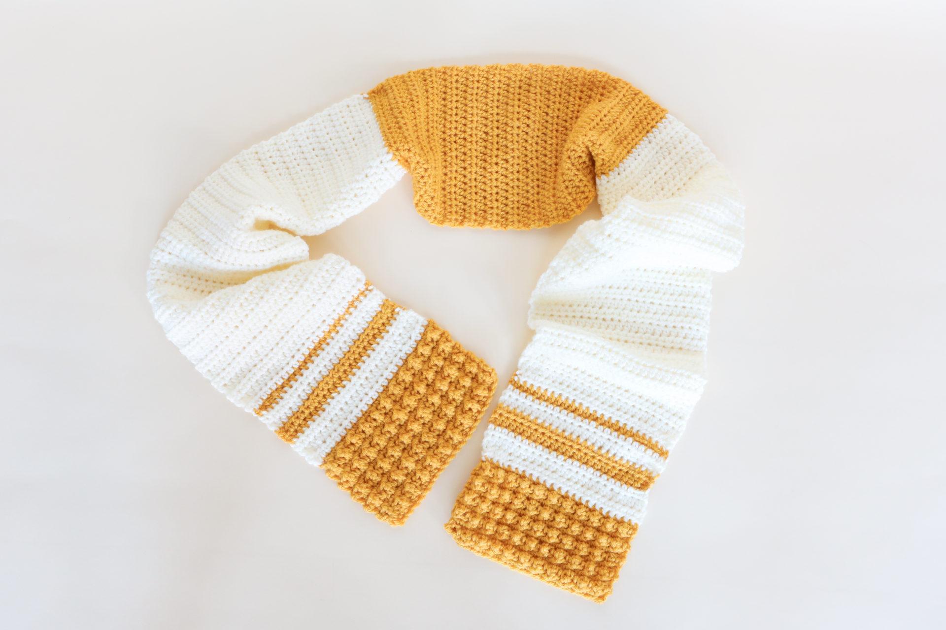 a stripy cream and yellow scarf lay flat on a cream background