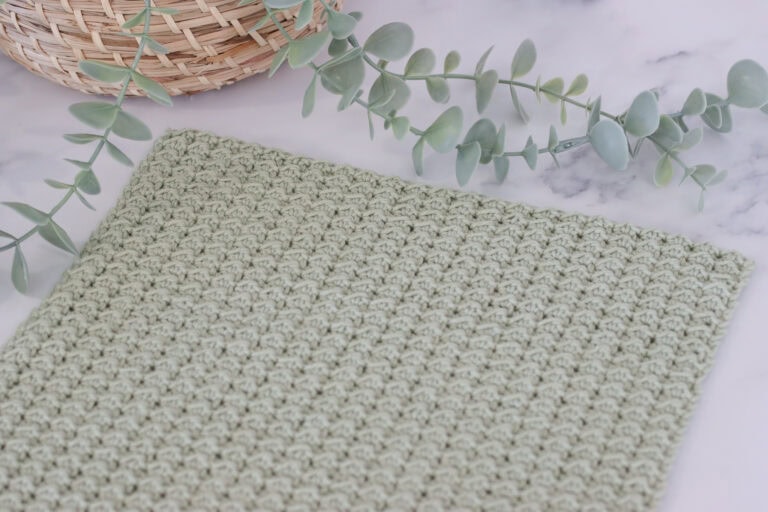 crochet swatch showing the even moss stitch in a pale green yarn