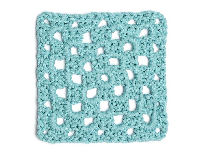 flat lay image of a teal blue crochet granny square on a white background