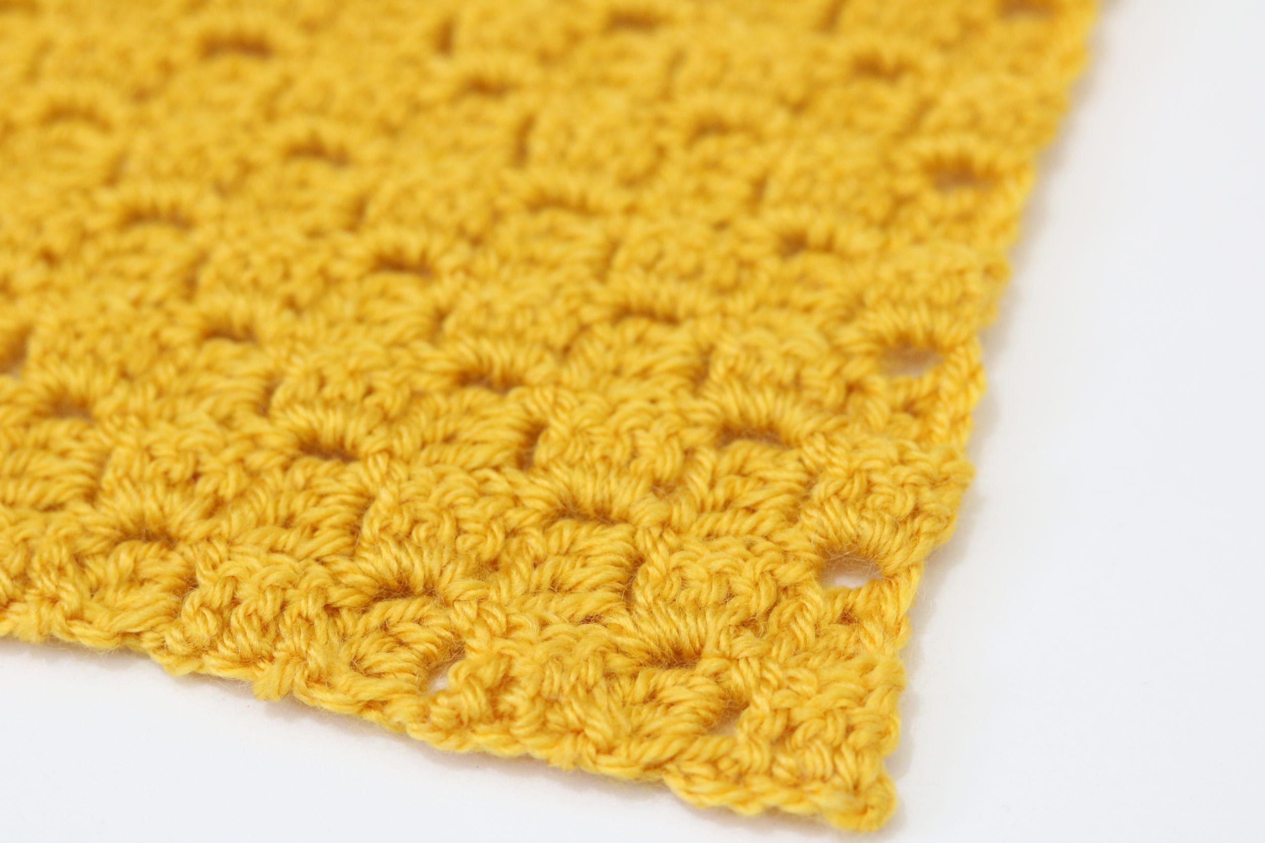 A swatch of corner to corner crochet in yellow yarn on a white background.
