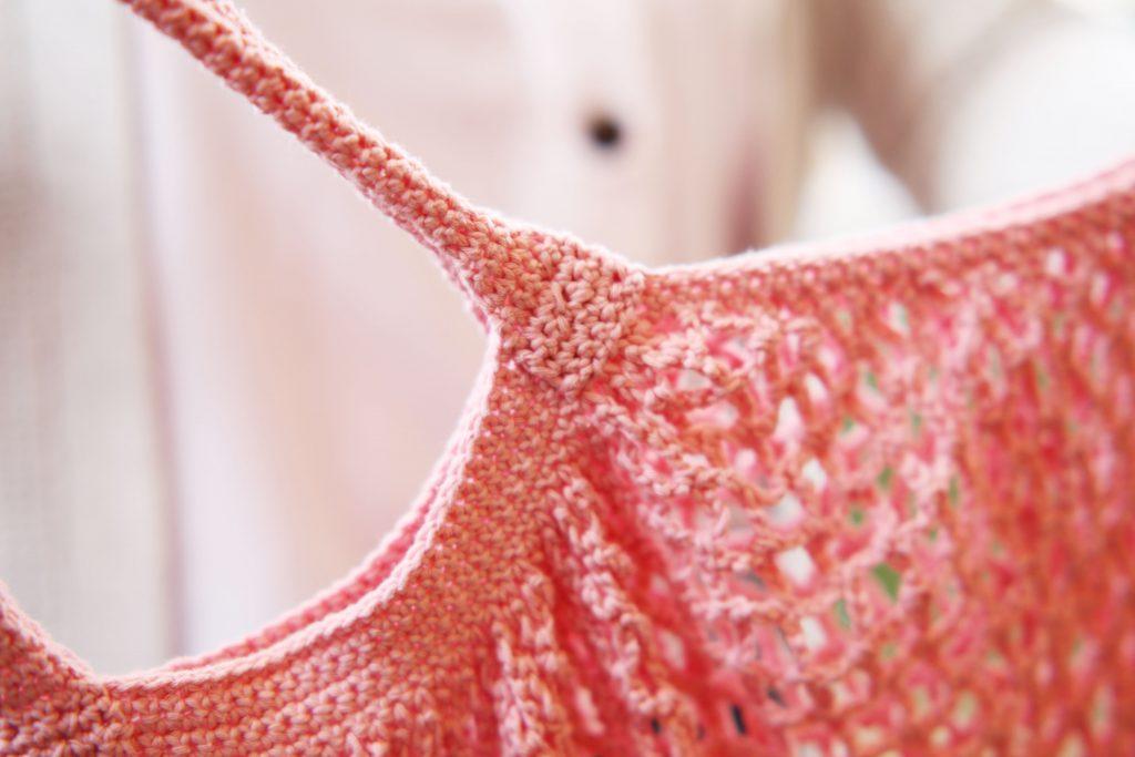 A close-up image of a coral crochet market bag. This is the Sundown Market Bag.