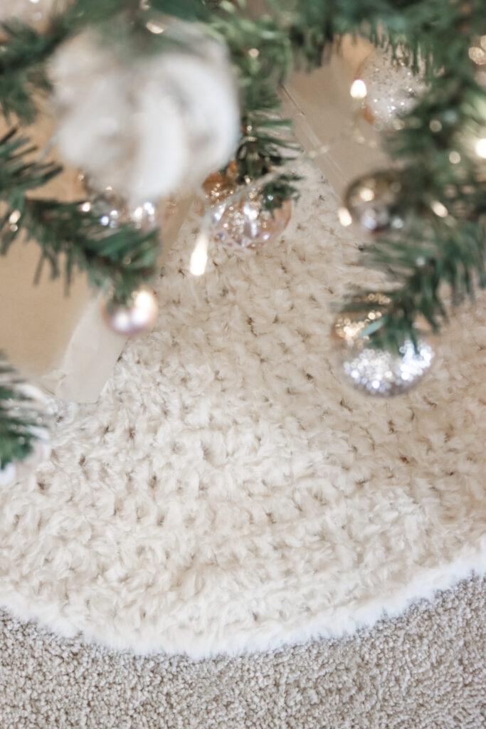 crochet tree skirt made from cream fluffy yarn shown around the base of a Christmas tree 