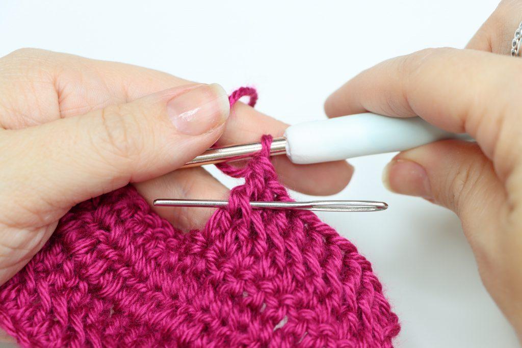 Fuchsia yarn and darning needle showing where to place stitch