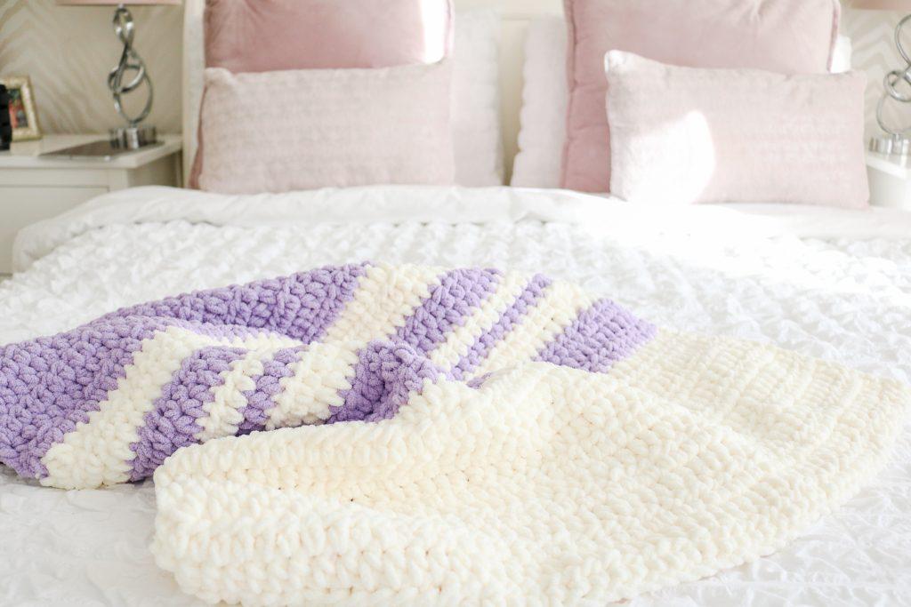 Purple and White Crochet Blanket draped over a white bed