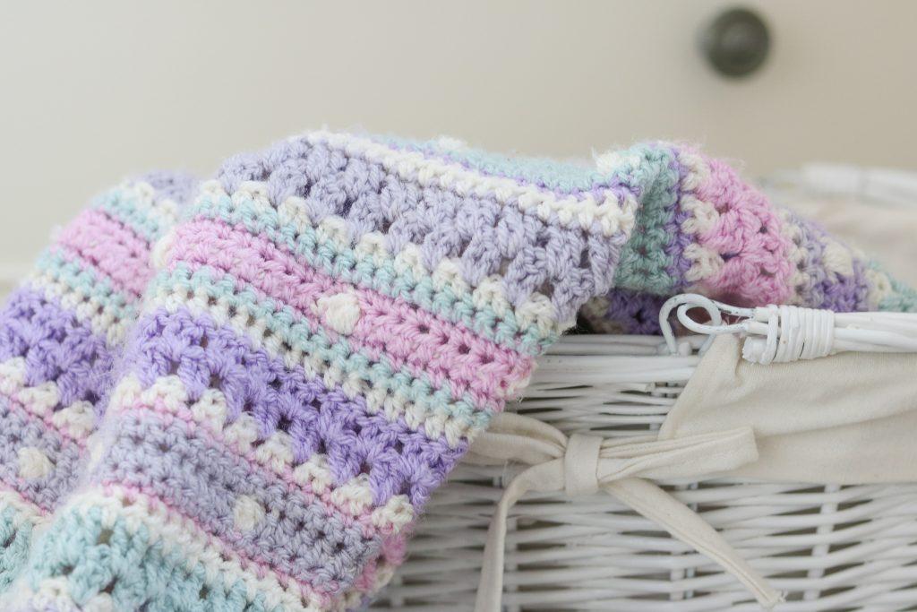a pastel coloured blanket sits in a white basket