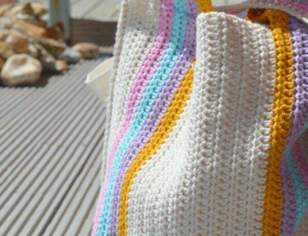 striped crochet beach bag with the beach in the background