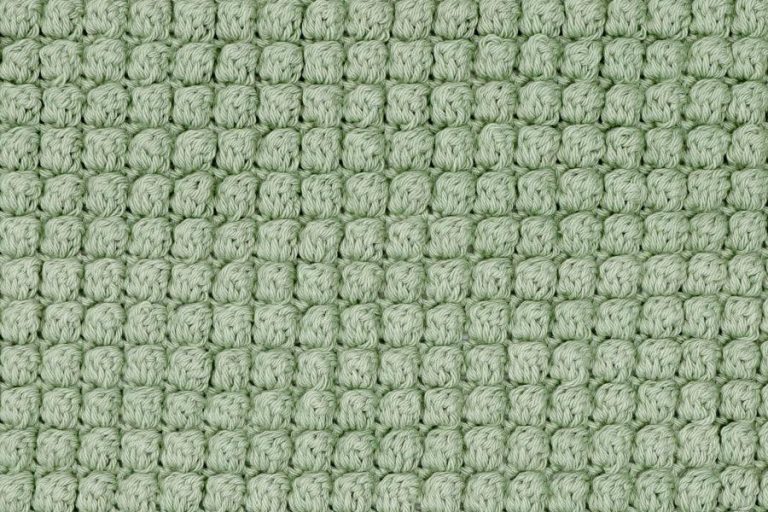 Close-up of a green crochet swatch made with the bobble stitch, showing a highly textured and uniform raised pattern.