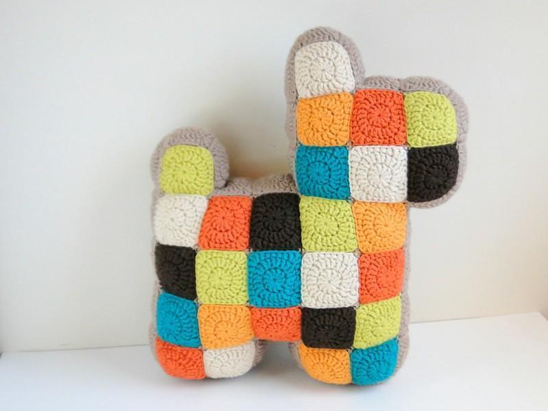 A dog-shaped cushion is made from a fresh, modern colour scheme of white, teal, lime, orange and black. 