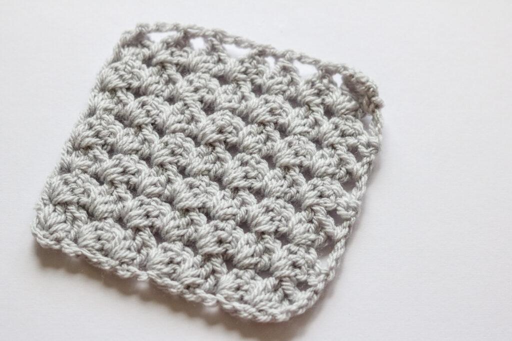 A grey C2C granny square sits on a white background. 