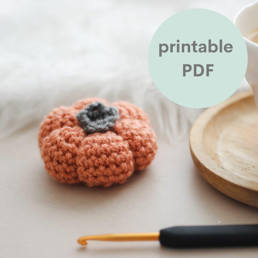 an image of a crochet pumpkin with a black and gold crochet hook in the foreground advertising the printable PDF