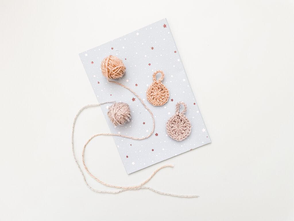 a flay lay image of two crochet gift tags in gold and silver tags lay on blue sparkly gift wrap. 