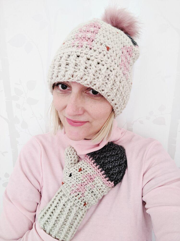 a women wearing a crochet hat and mittens made in pink and cream yarn. 