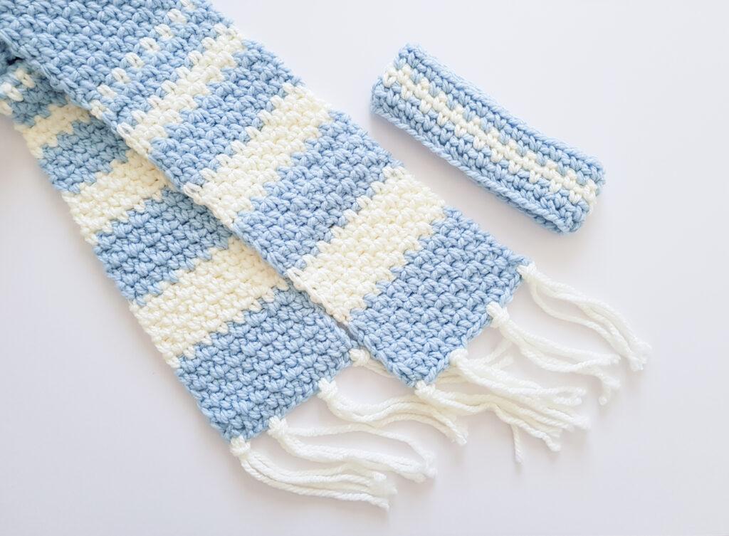 A blue and white scarf using the linen stitch with a matching headband on a white background.