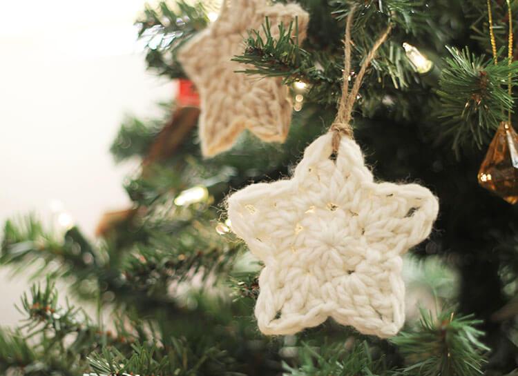 A white crochet star sits in a green christmas tree.
