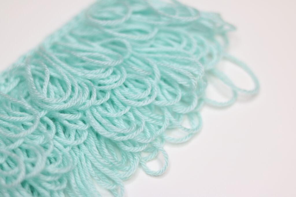 A swatch of loop stitch in aqua yarn is shown against a white background. 