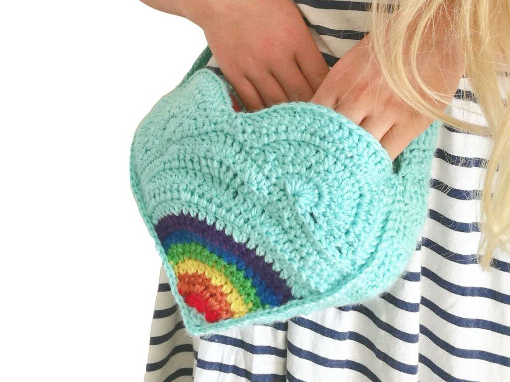 Hands in a crochet rainbow heart shaped bag