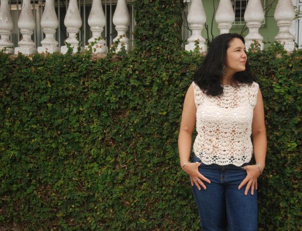 women wearing a cream crochet top stood in front of a hedge