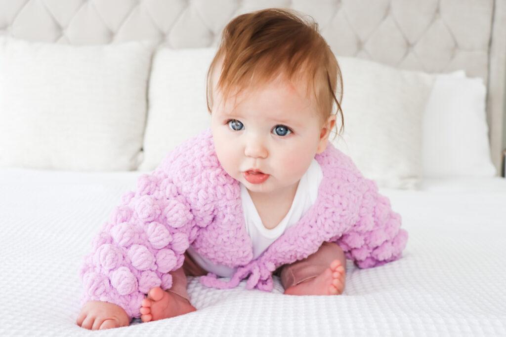 Baby in a crochet garment with puff sleeves