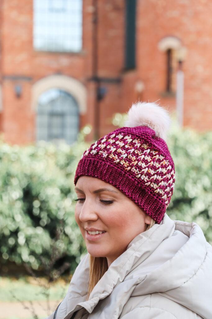 female stood outside wearing a crochet beanie hat in red and cream indie dyed yarn.