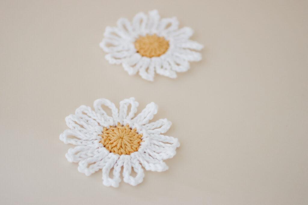 a yellow and white crochet daisy on a peach background