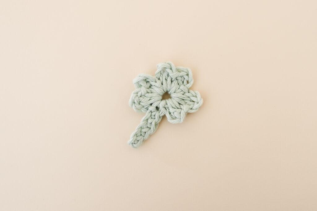 crochet shamrock made in pale green yarn on a cream backdrop