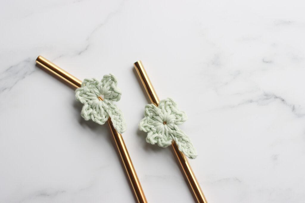 two crochet shamrock motifs attached to a gold metal straw