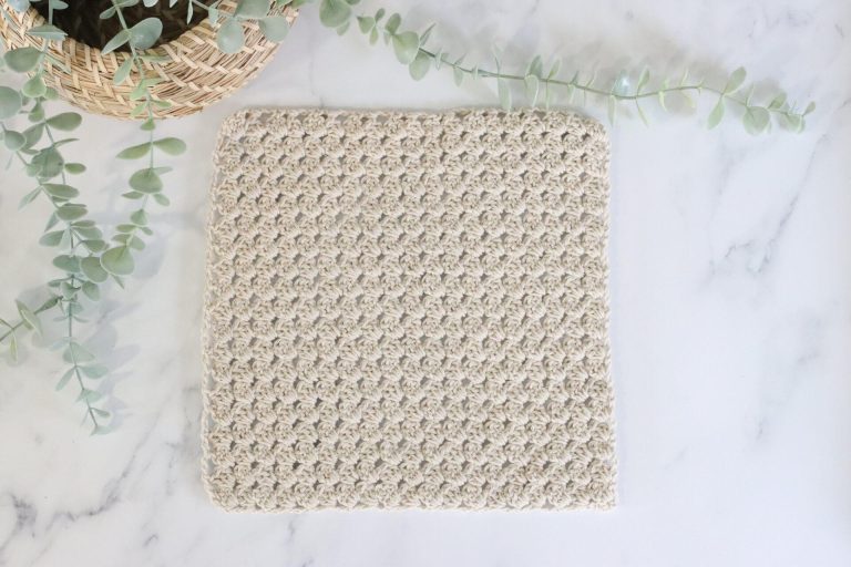 A corner to corner granny square on a plain background made with oatmeal coloured yarn.