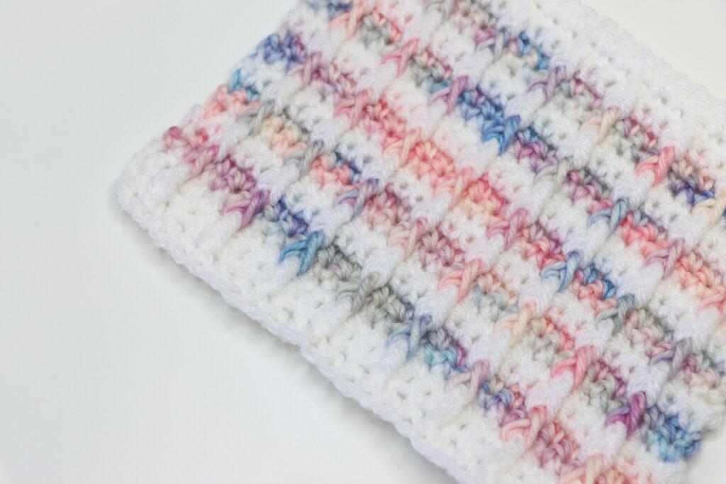 a flat lay images of a white and multi coloured crochet swatch of the bar stitch 