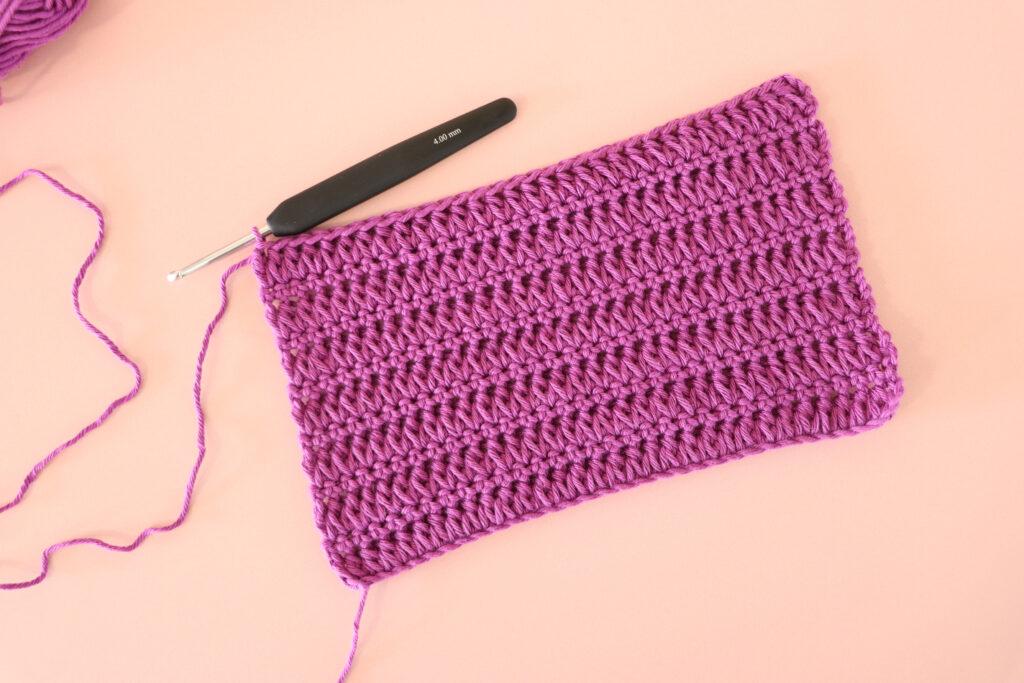 A pink swatch of Forked Cluster stitch with a black hook.