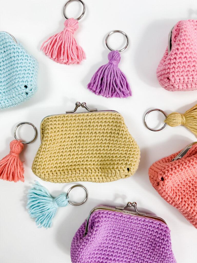 a flat lay image of crochet clasp purses in bright block colours and tassel key chains on a white background