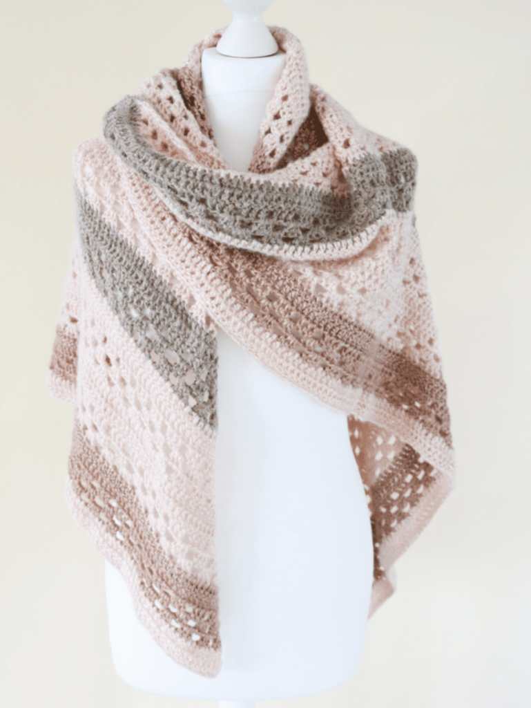 Crochet shawl on a white mannequin in peach, grey and brown yarn to showcase this crochet shawl pattern.