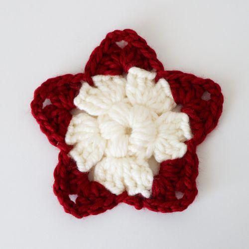 a flat lay image of a crochet star made in a chunky cream yarn for the first two rounds then a chunky red yarn for the final round using a 9mm hook to show you what it looks like. 