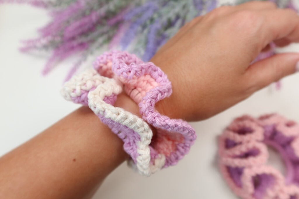 Two crochet scrunchies on a woman's wrist. 