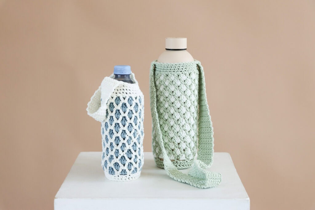 two crochet bottle holders side by side, one blue and white and one green and white.
